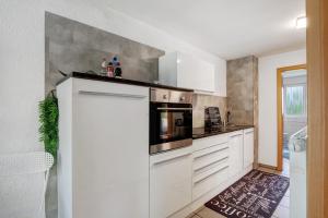 a kitchen with white cabinets and a stove at Ferienwohnung am Hof in Zwiefalten +16 photos