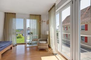 a room with a bed and a chair and large windows at Ferienwohnung am Hof in Zwiefalten