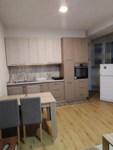 a kitchen with white cabinets and a wooden table with chairs at Stan na dan in Svilajnac