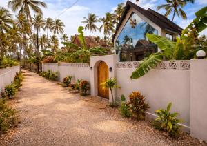 a house with a white fence and palm trees at Bahari Mirror Villas in Jambiani