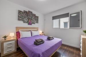 a bedroom with a purple bed with two towels on it at Casa Barriguita 2 in Playa Blanca