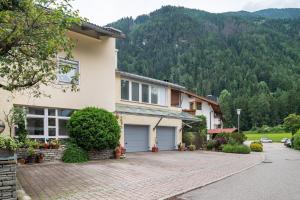 a house with a driveway in front of a mountain at Appartments Reichegger in Villa Ottone