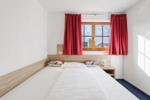 a bedroom with a large bed with red curtains at Untersee Appartements in Moos
