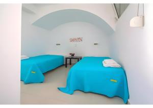 two beds in a room with blue sheets at Kaladi Rock Ammos in Avlemonas