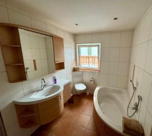 a bathroom with a tub and a sink and a toilet at Ferienwohnung Fuldawiesen in Schlitz
