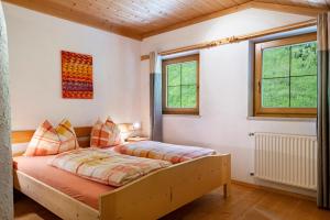 a bedroom with a bed and two windows at Eggerhof im Sarntal in Sarntal