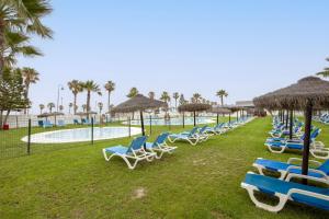 a row of lounge chairs and umbrellas at a resort at Sofie apartamento turístico in Roquetas de Mar