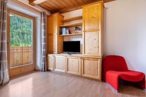a living room with a tv and a red chair at Eggerhof im Sarntal in Sarntal