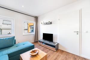 ein Wohnzimmer mit einer blauen Couch und einem Fernseher in der Unterkunft Fewo Al Backstuff in Hambuch