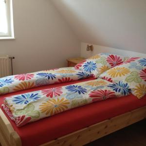 a bed with colorful sheets on top of it at Fácánkert Apartmanház in Tiszafüred