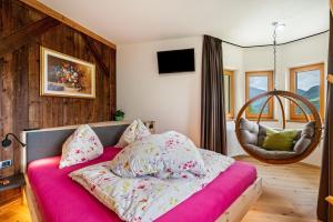 a bedroom with a pink bed with pillows and a chair at Weirerhof Lebm Gspiarn in Barbiano