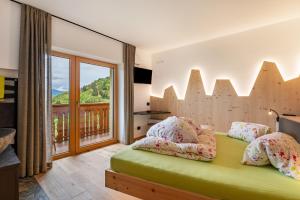 a bedroom with a green bed and a balcony at Weirerhof Lebm Gspiarn in Barbiano