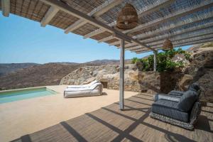 a patio with two chairs and an umbrella and a pool at Villa Vagia in Vayiá