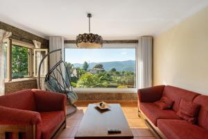 a living room with two red couches and a large window at Casa do Valado in Resende