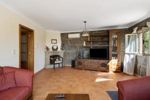 a living room with a tv and a stone wall at Casa do Valado in Resende