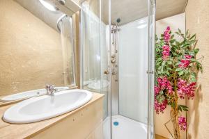 a bathroom with a sink and a shower with pink flowers at L'Ecurie in Guizengeard +16 photos