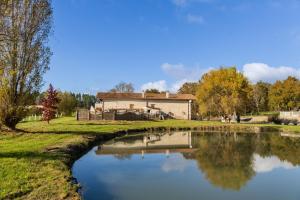 a building next to a pond in front of a building at L'Ecurie in Guizengeard