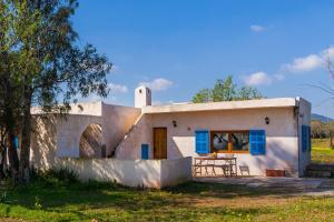a small white house with blue windows and a table at Sa Casona in Portocolom