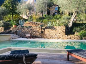 a pool with an umbrella next to a stone wall at Il wokini in Castel Vittorio