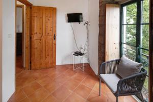 a room with a chair and a television on a wall at Quinta das Queimadas in Nordeste