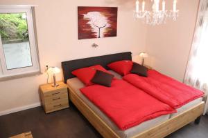 a bedroom with a bed with red sheets and a chandelier at Ferienwohnung Voege am Waldrand in Schmallenberg