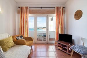 a living room with a couch and a tv at Apartamento Caravela in Armação de Pêra