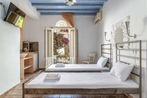 two beds in a room with white walls and blue ceilings at En Tino 1 in Tinos