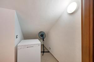 a small white room with a refrigerator and a ceiling at Casa chicken - mare, monti e bikers in Finale Ligure