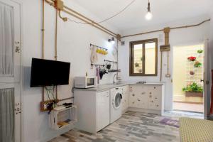 a laundry room with a washing machine and a tv at Las Sales Estudio in Moya