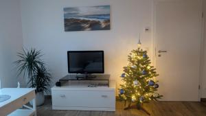 a christmas tree in a living room with a tv at Ferienwohnung Strandliebe in Lubmin