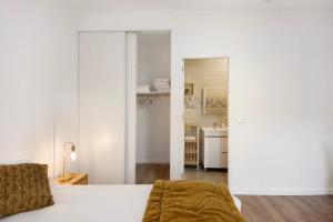 a white bedroom with a bed and a kitchen at Df Alojamentos e Suites in Coimbra