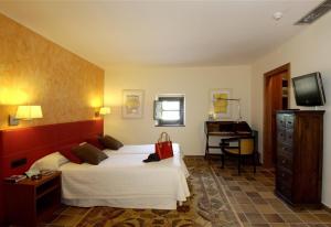 a bedroom with a bed and a desk and a television at luxury stone villa in Girona