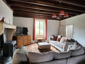 a living room with a couch and a tv at Le Gite du Bois Renard in Lorigné
