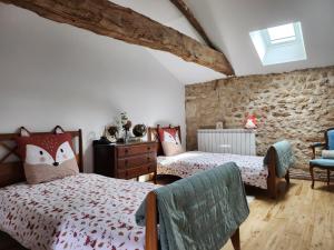 a bedroom with two beds and a stone wall at Le Gite du Bois Renard in Lorigné +29 photos