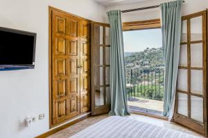 a bedroom with a large window and a tv at Castell Mirto - villa private pool in Calonge
