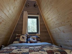 a bedroom in a cabin with a bed and a window at Le petit Sabotier in Soucht
