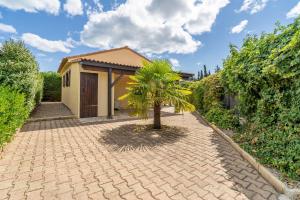 a small house with a palm tree in a driveway at Maison 6 Pers, proche de la plage in Vendres