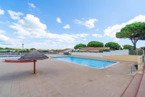 a large swimming pool with an umbrella next to it at Maison 6 Pers, proche de la plage in Vendres