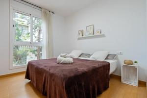 a white bedroom with a bed with a brown blanket at Dorada Apartment Lluna in Calafell