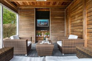 a patio with wicker chairs and a table and a tv at Nova Ferienhaus, 50qm in Ueckermünde