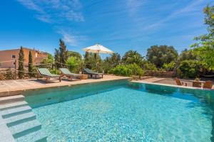 a swimming pool with two chairs and an umbrella at Son Sunyer in La Aranjasa