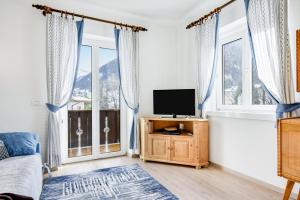 a bedroom with a bed and a tv and windows at Ciasa Christina in Moena