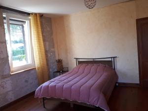 a bedroom with a bed with a pink blanket on it at Maison De Campagne in Barbaste