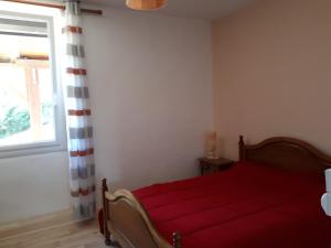a bedroom with a red bed and a window at Maison De Campagne in Barbaste +2 photos