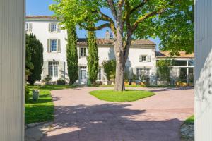 a large white house with a tree in front of it at Les gîtes du logis in Saint-Romain-de-Benet