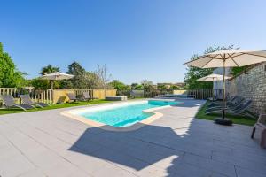 a swimming pool with chairs and an umbrella at Les gîtes du logis in Saint-Romain-de-Benet