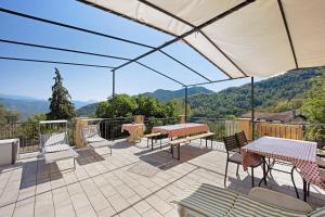 a patio with tables and chairs and a view of mountains at Il piccolo fienile in Vessalico