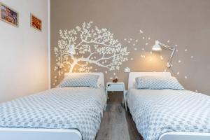 a bedroom with two beds and a tree mural on the wall at Appartamento Le Quattro Stagioni in Levico Terme