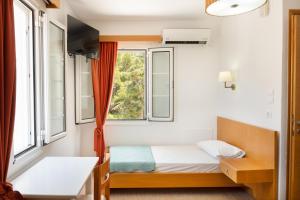 a bedroom with a bed and two windows at Calliope Maille Family House in Kalymnos
