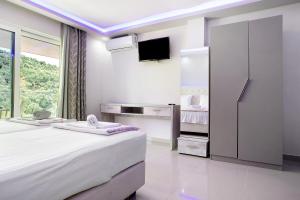 a white bedroom with a bed and a tv at Villa Dionysia Studio S6 in Alikanas +17 photos